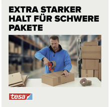 Ein Mann nutzt einen Paketbandabroller um einen Karton mit Klebeband zu verschließen mit Tesa Logo.