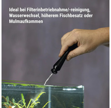 Main humaine dosant un activateur bactérien dans un aquarium pour maintenir la qualité de l'eau lors du nettoyage du filtre.