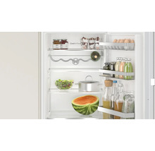 Réfrigérateur Bosch ouvert avec technologie CoolAirflow, rempli d aliments, de bouteilles et d une pastèque sur les clayettes.