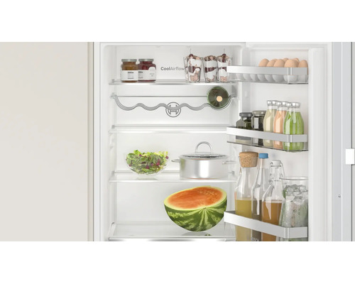 Réfrigérateur Bosch ouvert avec technologie CoolAirflow, rempli d aliments, de bouteilles et d une pastèque sur les clayettes.