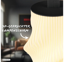 Detailansicht einer modernen Leuchte mit einem strukturierten 3D gedruckten Lampenschirm und einem Trageband in einem wohnlichen Raum.