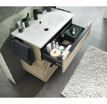 Meuble sous vasque aspect bois avec lavabo blanc et tiroir ouvert avec organisateur et porte serviette dans la salle de bain.
