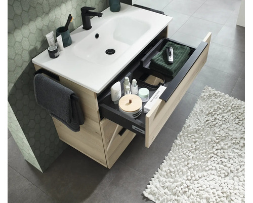 Meuble sous vasque aspect bois avec lavabo blanc et tiroir ouvert avec organisateur et porte serviette dans la salle de bain.