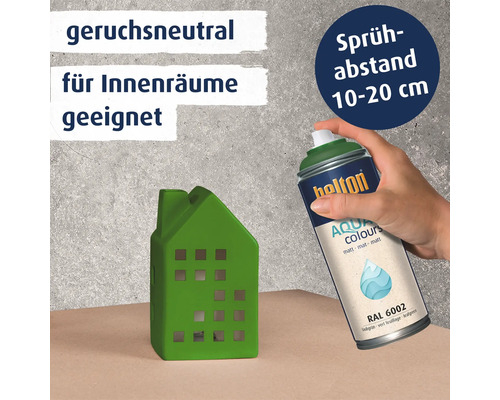 Eine Hand sprüht mit einer Belton Aqua Colours Sprühdose auf ein kleines dekoratives Haus aus Keramik.