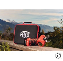 Sécateur à batterie FELCO avec mallette de transport devant un paysage de montagne. (Image AI modified or generated)