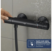 Grohe Thermostat Duscharmatur mit Mengenregulierung und Handbedienung an einer Wandfliese mit Wassertropfen.