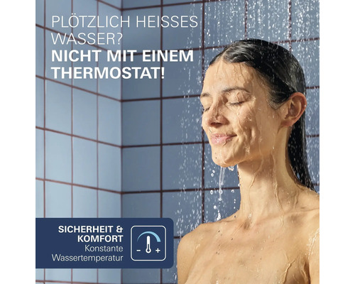 Eine Frau duscht in einem gefliesten Badezimmer unter einem Duschthermostat, das für eine konstante Wassertemperatur und Sicherheit sorgt.