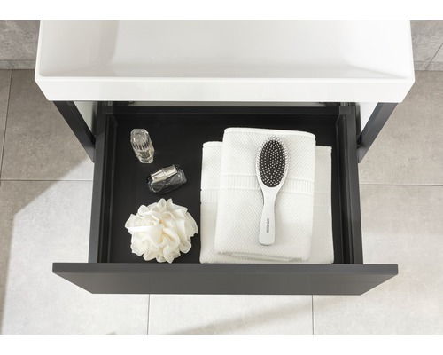 Offene Schublade mit Handtüchern, Haarbürste, Badeschwamm und Parfümflaschen