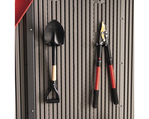 An der Wand hängen ein Spaten und eine Astschere.