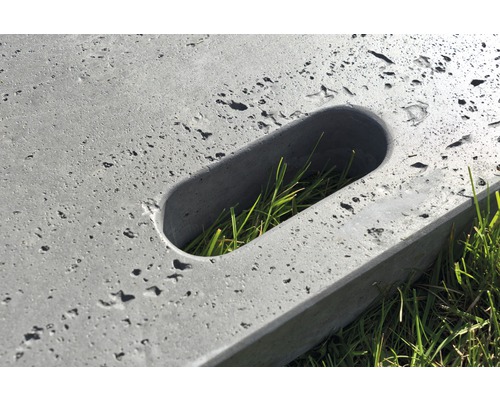 Detailansicht einer Betonplatte mit länglichem Loch und Gras