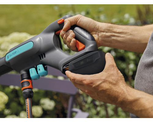 Une personne insère une batterie dans un outil de jardin Gardena.