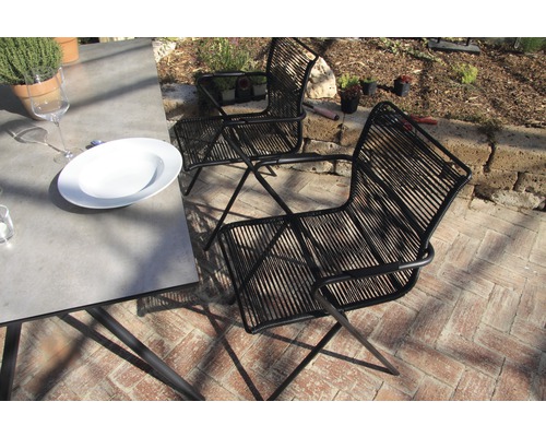 Scène avec deux chaises en cordage noires et une table à manger à l''extérieur