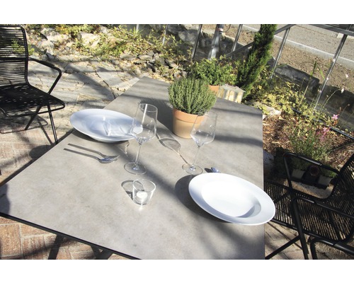 Table à manger dressée avec vaisselle, verres, couverts et plante en pot à l''extérieur