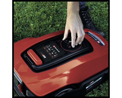 Gros plan d''un robot tondeuse avec une main tournant un bouton