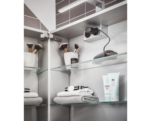 Spiegelschrank mit Kosmetikartikeln, Handtüchern und Rasierer auf Glasablagen