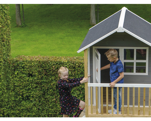Maisonnette en bois avec deux enfants dans le jardin.