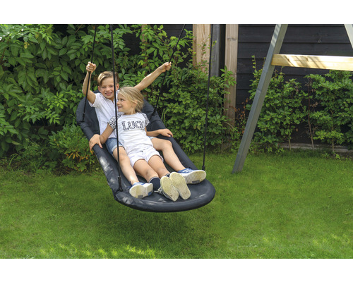 Deux enfants se balancent sur une balançoire nid d''oiseau dans le jardin.