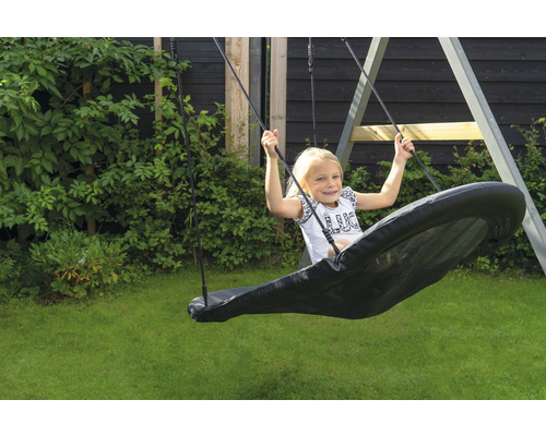 Fille sur une balançoire à plateau dans le jardin.