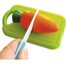 Une carotte en jouet est coupée sur une planche à découper avec un couteau