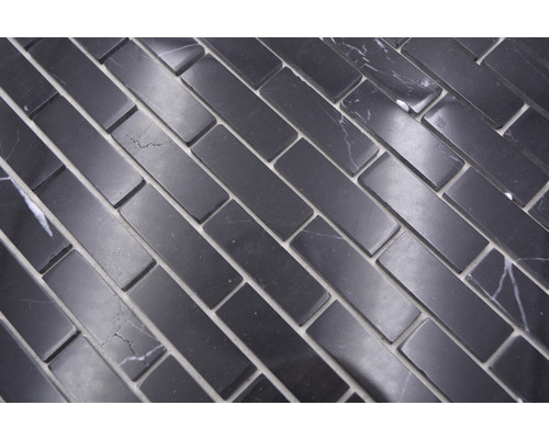 Rechteckige Mosaikfliesen aus Naturstein, verlegt im Fischgrätmuster.