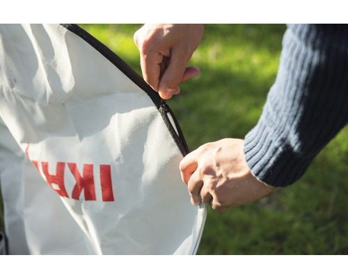 Une personne ferme un sac à feuilles avec une fermeture éclair.