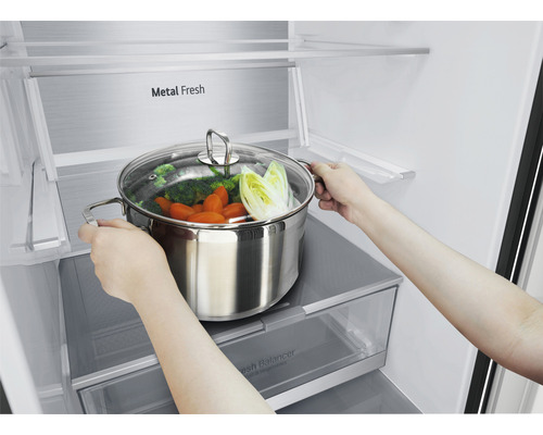 Person stellt Kochtopf mit Gemüse in den Kühlschrank.