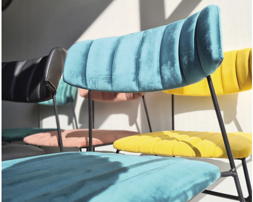 Plusieurs chaises recouvertes de velours avec pieds en métal sont disposées dans la pièce.