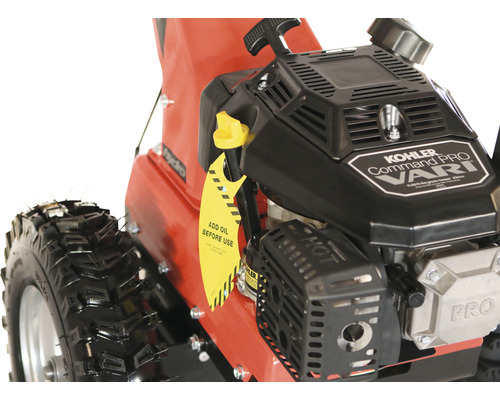 "Detailaufnahme einer Schneefräse mit Kohler Command Pro Motor und gelbem Anhänger mit dem Hinweis ""Vor Gebrauch Öl nachfüllen"""