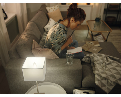 Frau sitzt auf Sofa mit Tischleuchte und Notizbuch