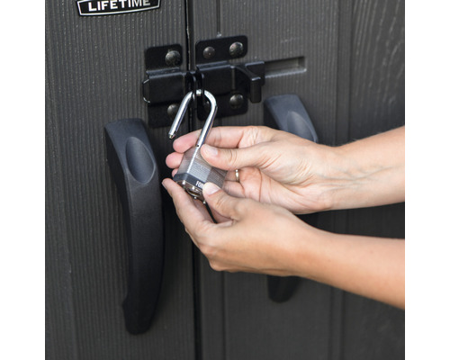 Eine Person schliesst ein Vorhängeschloss an einem Schuppen an.