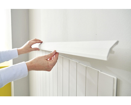 Une personne fixe des panneaux muraux blancs au mur
