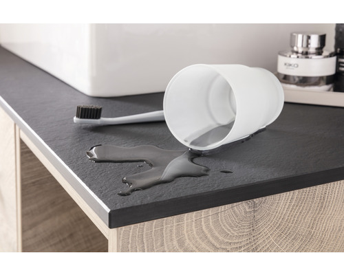 Scène de salle de bains avec un gobelet blanc renversé, une brosse à dents et de l''eau renversée sur un lavabo.