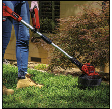 Une personne utilise un coupe-bordure Einhell dans le jardin.