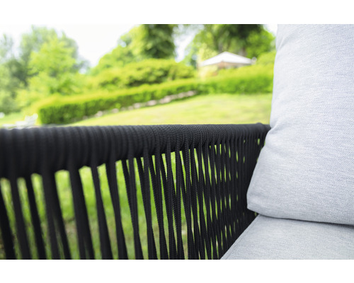 Detailaufnahme eines Gartensessels mit geflochtenem, dunklem Gestell und hellem Polster