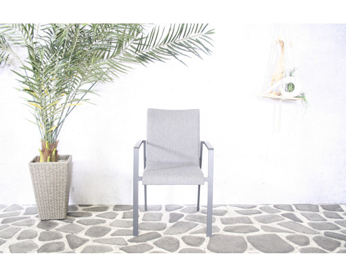 Fauteuil de jardin en aluminium et tissu avec accoudoirs devant un mur blanc