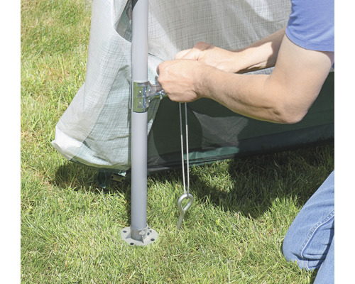 Detailaufnahme einer Person, die ein Pavillon mit Heringen im Gras befestigt