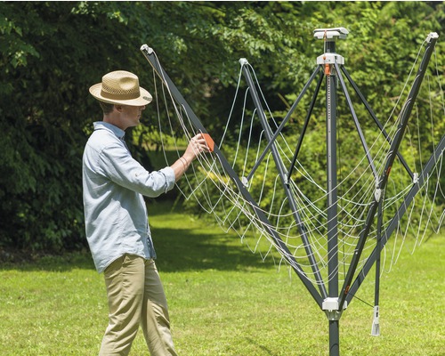 Mann bedient Wäschespinne im Garten