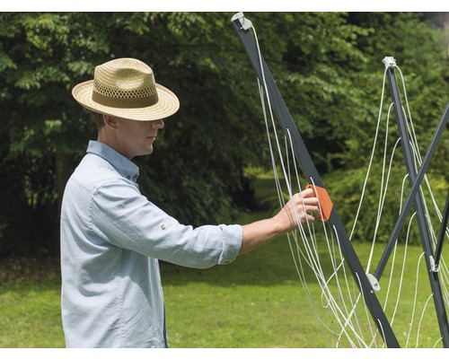 Mann beim Aufspannen einer Wäschespinne im Garten.