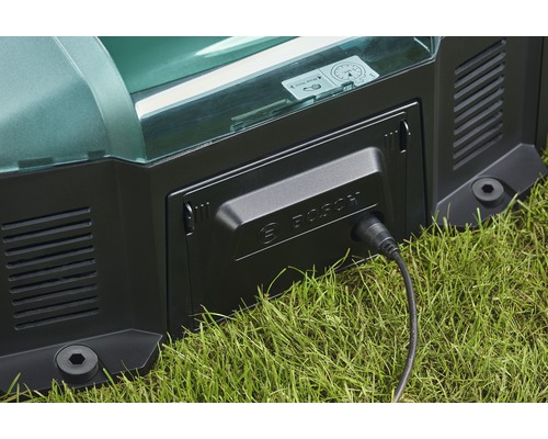 Gros plan d''un robot de tonte en charge avec un câble de charge branché et le logo Bosch