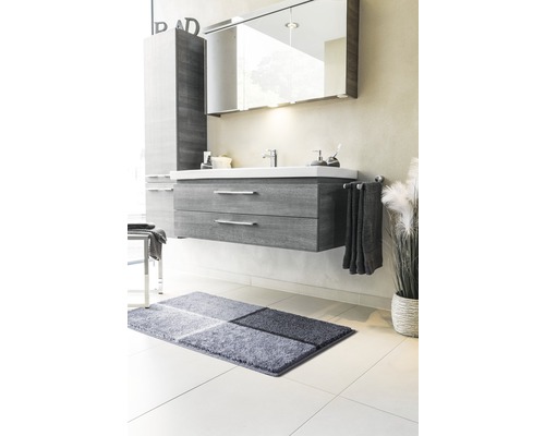 Badezimmer mit Waschtischunterschrank, Spiegelschrank, Handtuch und Badteppich