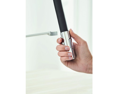 Eine Hand hält eine verstellbare Duschstange aus Metall