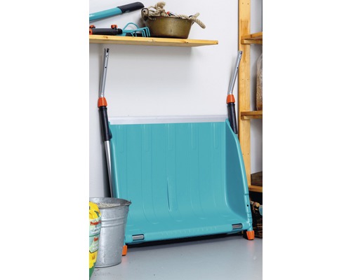 Une pelle à neige bleue est posée contre le mur dans un local de stockage.