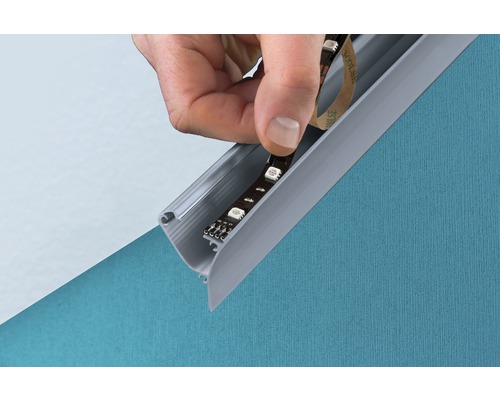 Hand befestigt LED Streifen in ein Aluminiumprofil an einer Wand.