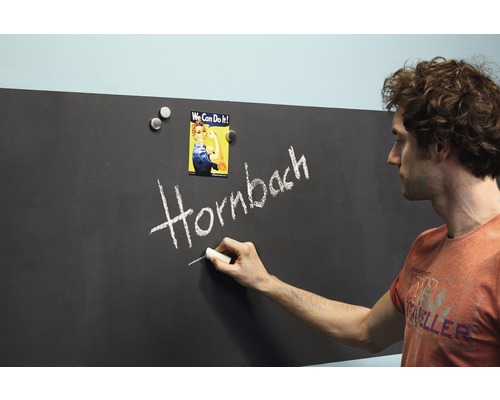 Mann schreibt mit Kreide Hornbach auf eine Tafel