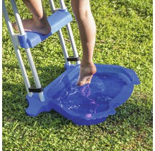 Personne utilisant une échelle de piscine avec un bain de pieds sur une pelouse