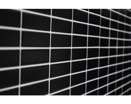 Mauer aus schwarzen, rechteckigen Fliesen mit hellem Fugenmörtel