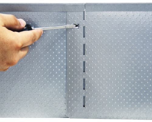 Eine Person verwendet einen Schraubendreher an einer Lochblechplatte.