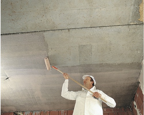Un homme peint un plafond avec un rouleau de peinture.