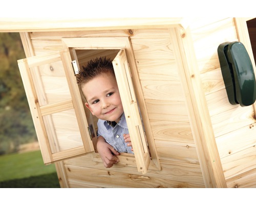 Garçon regarde par la fenêtre d''une cabane en bois