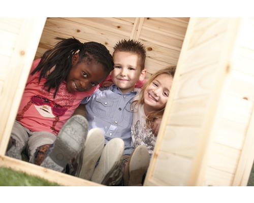 Trois enfants sourient à l''intérieur d''une cabane en bois.